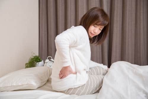 床時の辛い腰痛に悩む女性